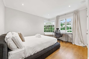Ein Schlafzimmer mit Bett, Schreibtisch und einem Fenster mit Vorhängen.