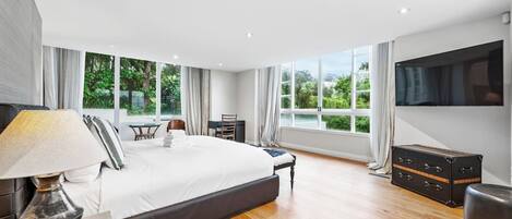 Una habitación de hotel moderna con una cama grande, un escritorio, una silla, un televisor y un armario.