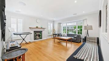 A spacious living room with a fireplace, a sofa, a coffee table, and a striped rug.