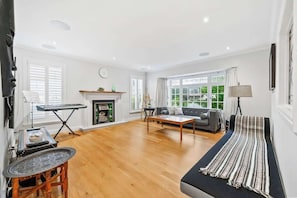 Ein geräumiges Wohnzimmer mit Kamin, einer Couch, einem Couchtisch und einem Streifen Teppich.