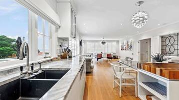 A modern kitchen with a large island, a dining area with a long table, and a view of the outdoors.