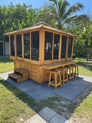 A wooden structure with a bench and stools, a small table, and a step leading to a door. - Quaint 3 bedroom 2 bath house centrally located in Saint Petersburg (Pinellas Park)