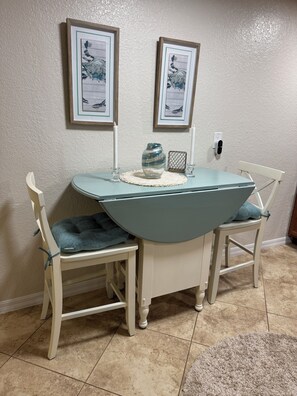A dining area with a table and two chairs, framed artwork on the wall, and a vase on the table. - Quaint 3 bedroom 2 bath house centrally located in Saint Petersburg (Pinellas Park)