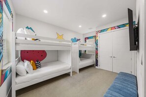 Ein Zimmer mit Etagenbetten, einem Fernseher und farbenfroher Wandgestaltung.