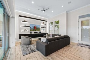 A modern living room with a grey sofa, a grey armchair, and a flat-screen TV mounted on the wall. - The Reserve at Reunion-TT491 (Kissimmee)