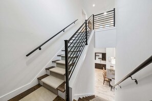 Eine Treppe mit Handlauf, Teppichstufen und Blick auf einen Küchenbereich.