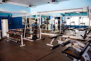 Ein Fitnessraum mit Gewichten, Spiegeln und einer blauen Wand.