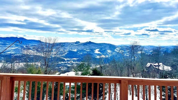 A wooden deck with a view of snow-covered mountains and a partly cloudy sky. - Amazing Mountain Views, Walk to BMR & Downtown! (Banner Elk)