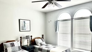 A bedroom with two beds, a ceiling fan, a nightstand, a lamp, a framed picture, and a window with blinds. - Amazing Mountain Views, Walk to BMR & Downtown! (Banner Elk)
