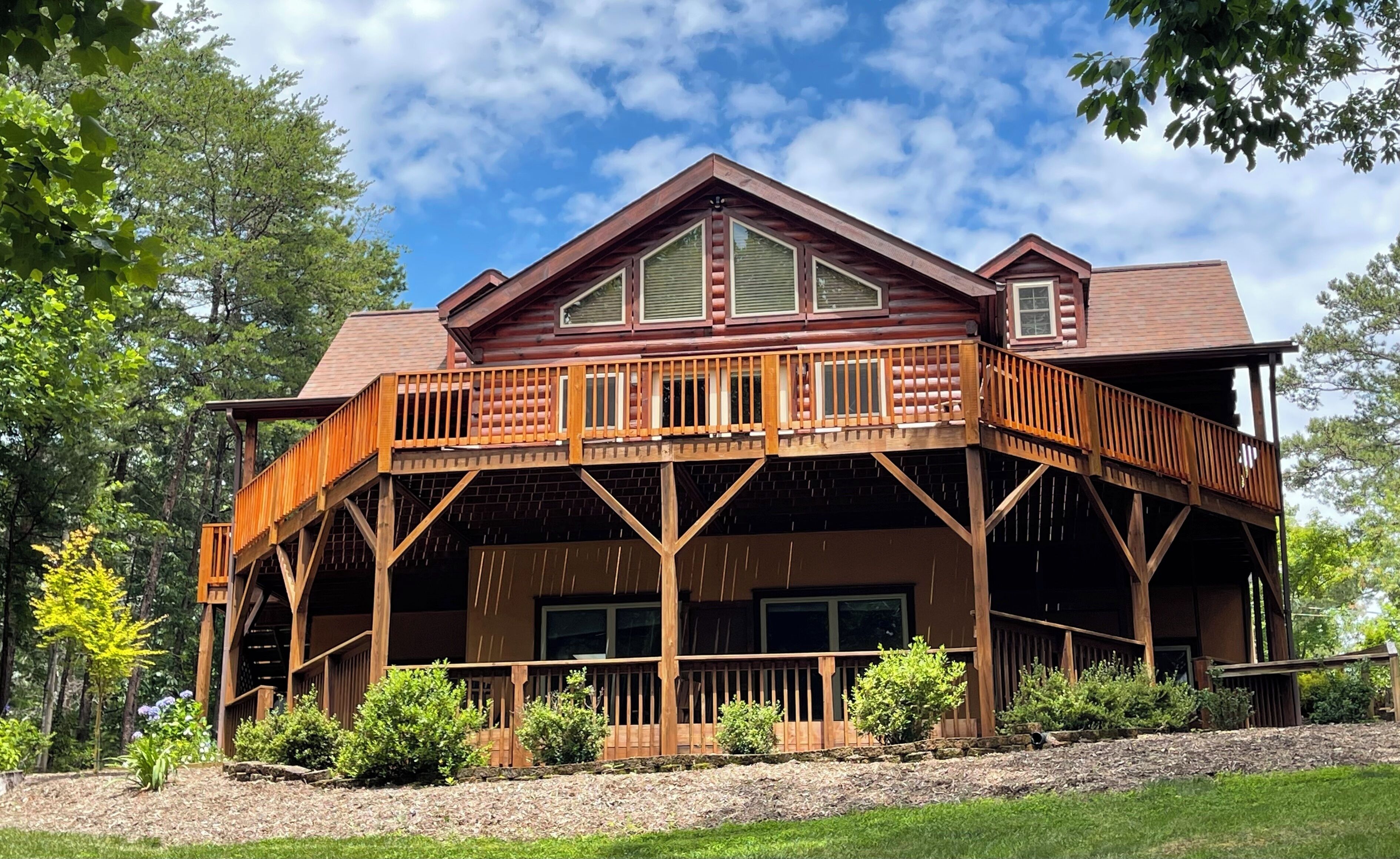 A two-story log cabin with a wooden deck and a large garage.