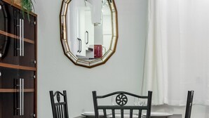 Een eetruimte met een houten tafel, zwarte stoelen en een spiegel aan de muur.