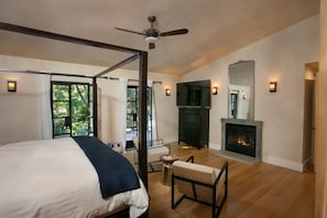 A bedroom with a four-poster bed, a fireplace, a television, and a view of greenery outside. - Kenwood Villa - 3BD, Pool, Spa, Sport Court (Kenwood)