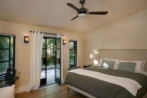 Ein Schlafzimmer mit einem Bett, einem Deckenventilator und einer Glasschiebetür, die zu einem Außenbereich führt.