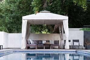 Un espace extérieur aménagé, abrité et doté de sièges, avec une piscine en premier plan.