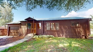 Eine Holzhütte mit Garage, einer Veranda und einem kleinen Garten.