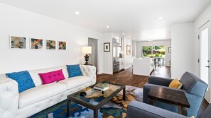 Ein modernes Wohnzimmer mit einem weißen Sofa, einem Couchtisch und einem Essbereich mit Tisch und Stühlen.
