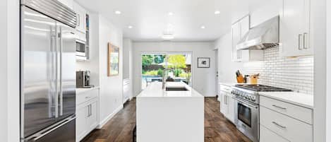 Una cocina moderna con armarios blancos, electrodomésticos de acero inoxidable y una isla central.
