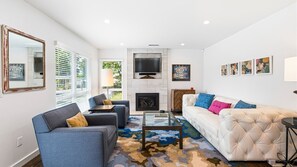 A living room with a fireplace, a sofa, a coffee table, and a TV. - Private Pool | East Sonoma | By Homewood Winery | 2BR, Sleeps 4, Quiet Street (Sonoma)