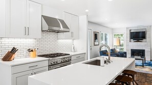 Een moderne keuken met witte kasten, een roestvrijstalen afzuigkap en een centraal eiland met een spoelbak.