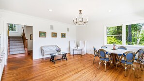 A spacious room with hardwood flooring, a dining table with chairs, a sofa, and a chandelier. - Monthly Stay | Vineyard Pool, Hot Tub | 3BR Home | Sleeps 6, Pets OK, West Dry Creek (Healdsburg)