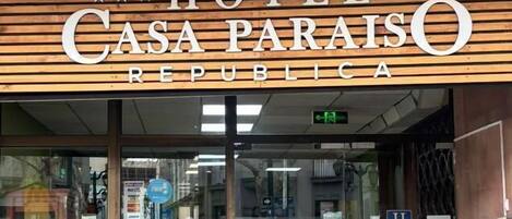 La entrada al Hotel Casa Paraíso República con fachada de madera y puertas de vidrio.