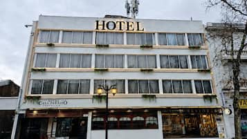 Um hotel com vários andares e uma placa com a palavra 'HOTEL' sobre a entrada.