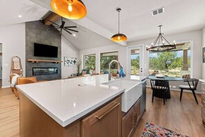 A modern kitchen with a large island, built-in oven, and a dining area with a view. - Far View Hideout - Hot tub & Fire pit (Fredericksburg)