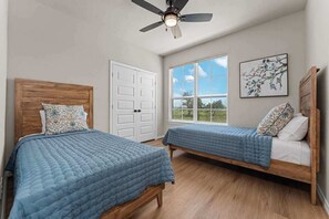 A bedroom with two wooden beds, a ceiling fan, a large window, and a door. - Far View Hideout - Hot tub & Fire pit (Fredericksburg)