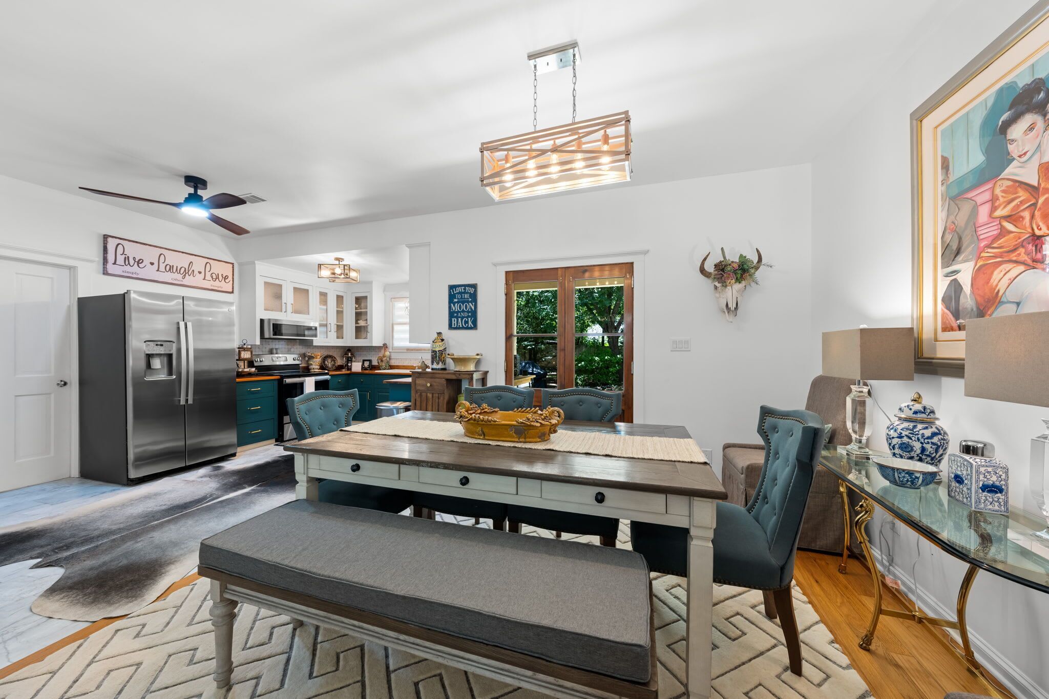 Una cocina moderna con una isla central, electrodomésticos de acero inoxidable y un comedor con un banco y sillas.