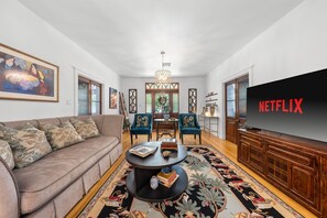 A living room with a sofa, chairs, a coffee table, a TV, and a decorative rug. - Hackberry Haus - Hot Tub (Fredericksburg)