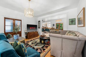 A modern living room with a television, a sofa, a coffee table, and a patterned rug. - Hackberry Haus - Hot Tub (Fredericksburg)
