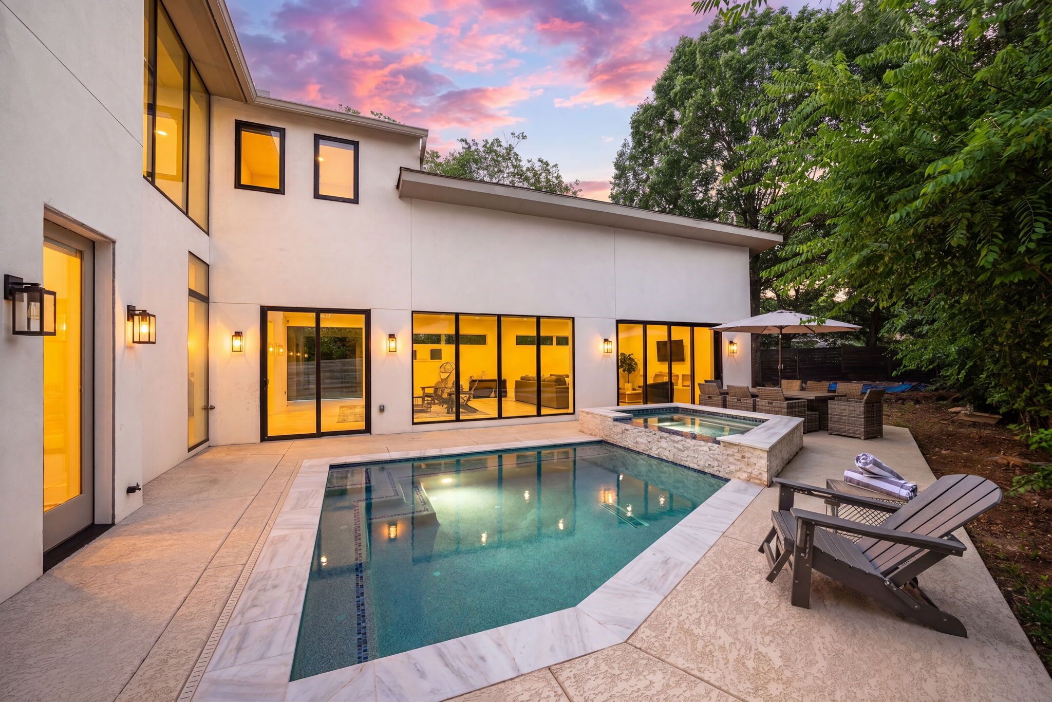 A modern house with a swimming pool, outdoor seating, and a patio area.