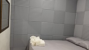 A bedroom with a bed, a nightstand, a mirror, and a wall with a geometric pattern. - Edícula 55 M2 aceita pequenos pets (Foz do Iguaçu)
