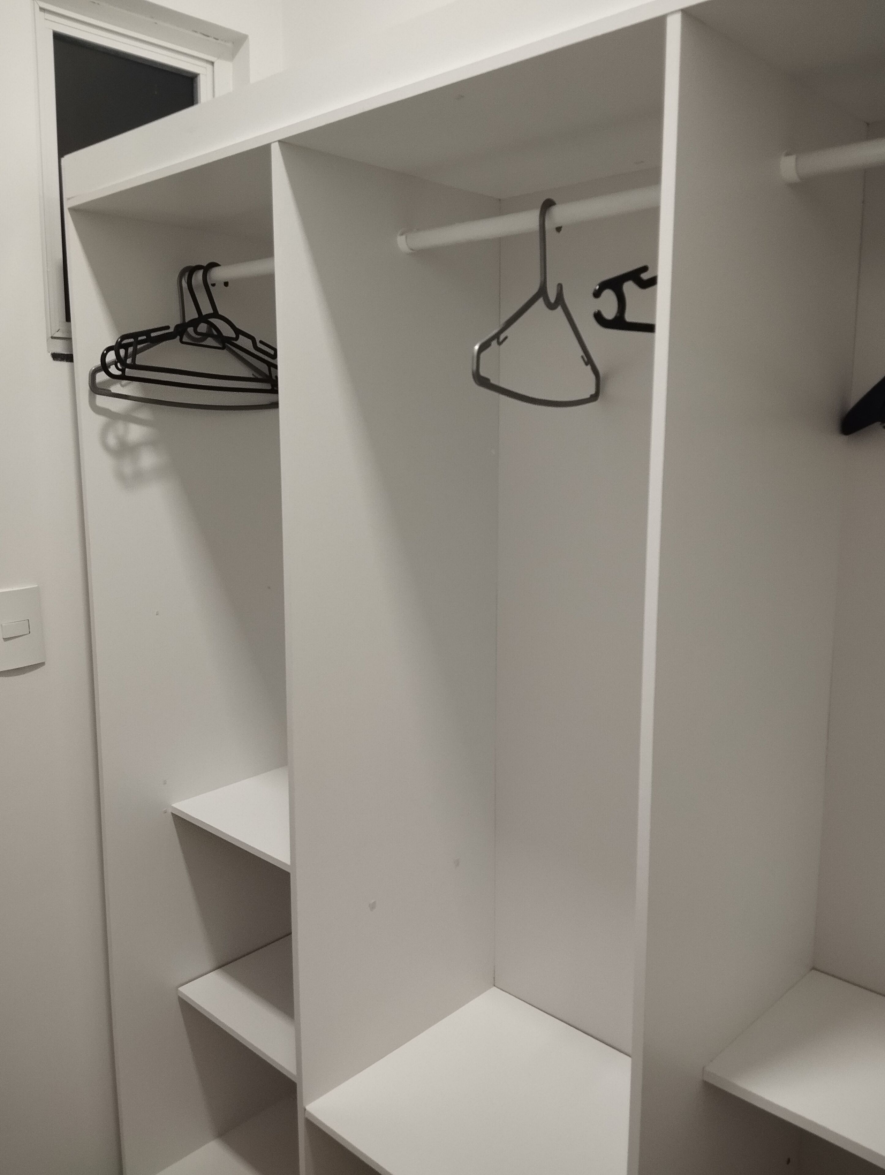 A white closet with shelves and a hanging rod.