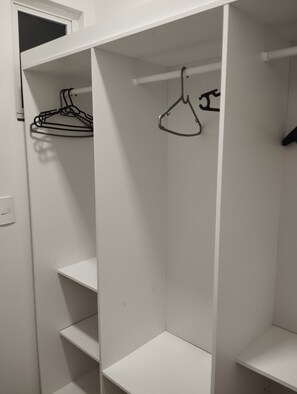 A white closet with shelves and a hanging rod.