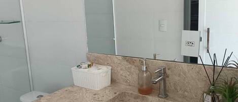 Et moderne badeværelse med en marmorvask, en glas sæbedispenser og et toilet.