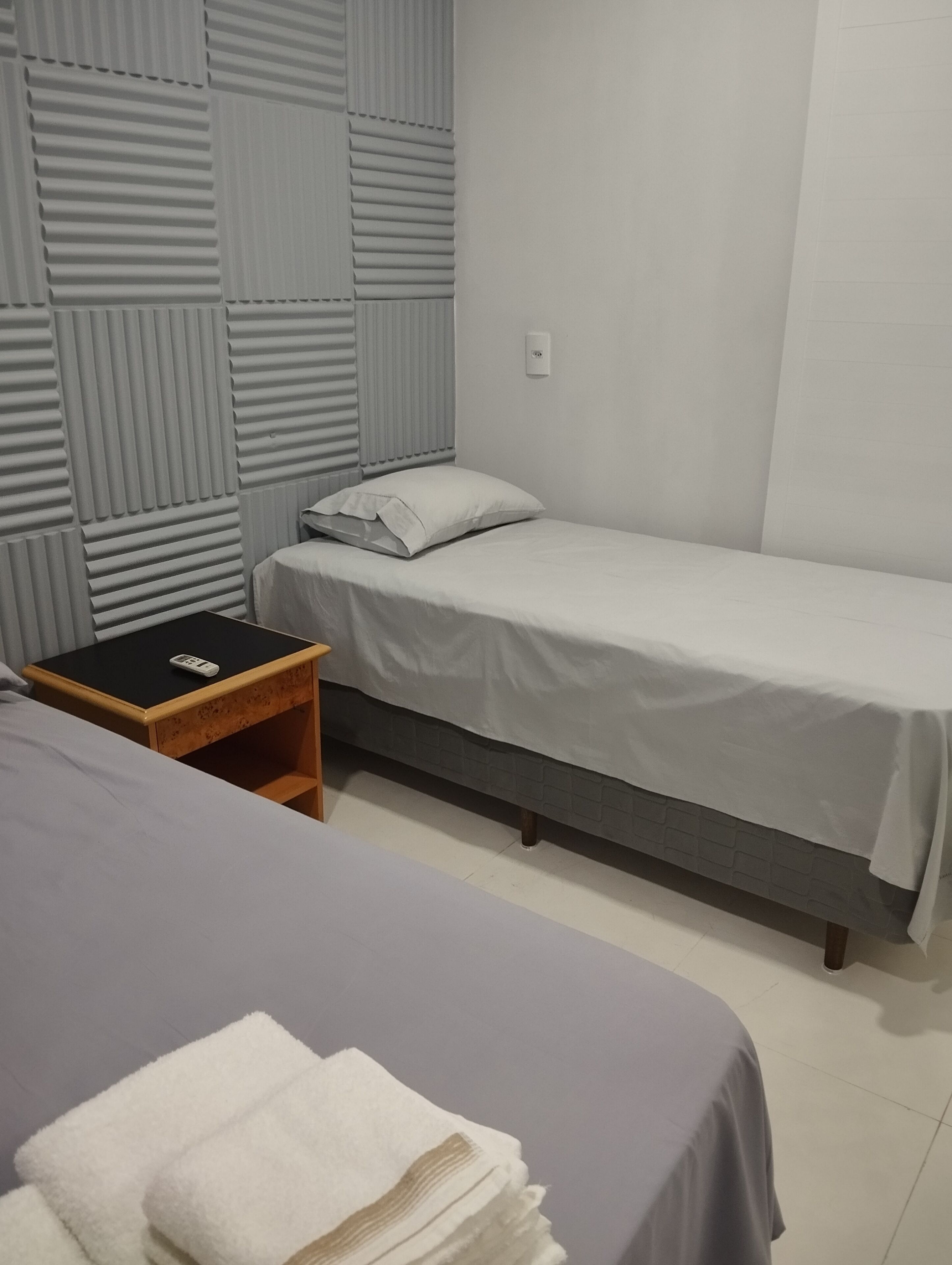 Una habitación con una cama individual, una mesita de noche y un interruptor de luz en la pared.