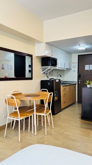 A compact kitchen with a microwave, refrigerator, and wooden dining table with chairs. - Condo in Araneta City Cubao • Walk to Coliseum • Smart Lock • Parking • Pool (Quezon City)