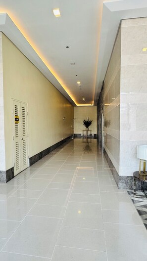 A hotel corridor with a tiled floor, a reception desk, and a wall-mounted plant. - Condo in Araneta City Cubao • Walk to Coliseum • Smart Lock • Parking • Pool (Quezon City)