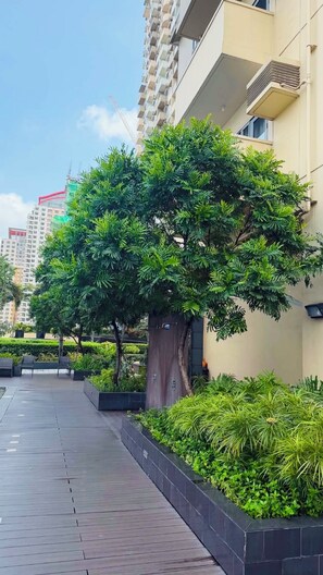 Un chemin bordé de verdure et un bâtiment doté de balcons.