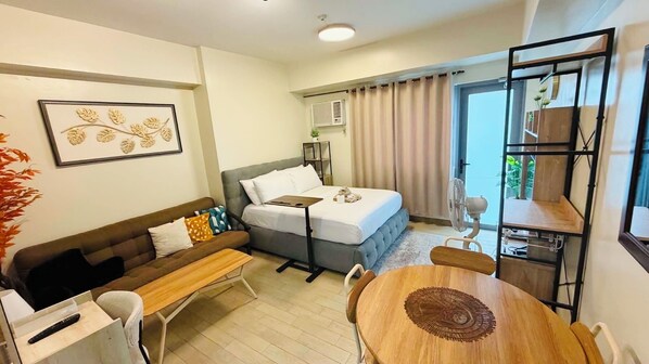 Une chambre d’hôtel avec un lit, un canapé, une table à manger et un petit balcon.