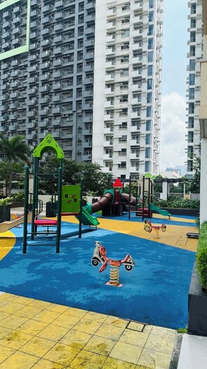 A playground with a slide, climbing structures, and a seesaw. - Condo in Araneta City Cubao • Walk to Coliseum • Smart Lock • Parking • Pool (Quezon City)