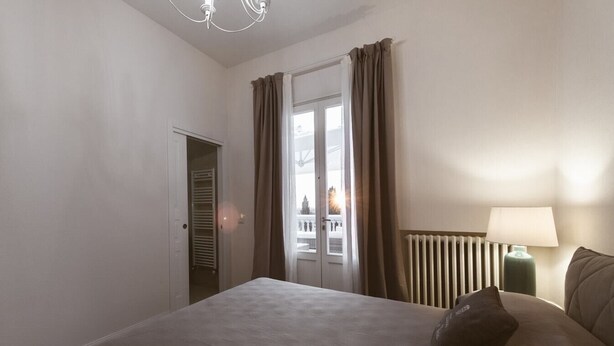 A hotel room with a bed, a nightstand, a lamp, a radiator, and a view through a door. - Large Country Villa with Swimming Pool in Tuscany (La Chiesa Collegozzi)