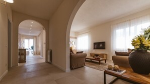 A spacious living area with a sofa, coffee table, and a TV. There is a large vase with flowers on a side table. - Large Country Villa with Swimming Pool in Tuscany (La Chiesa Collegozzi)