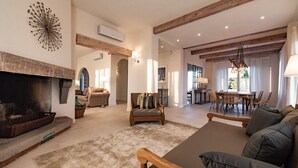 A spacious living room with a fireplace, a dining area with a chandelier, and a view of the outdoors. - Large Country Villa with Swimming Pool in Tuscany (La Chiesa Collegozzi)