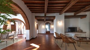 A spacious interior with a wooden ceiling, a dining area with chairs, a television, and a staircase leading to another level. - Large Country Villa with Swimming Pool in Tuscany (La Chiesa Collegozzi)