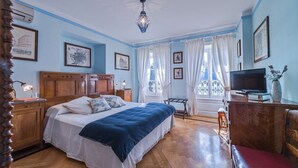 Een slaapkamer met een houten bed, een televisie en een bureau met een stoel.