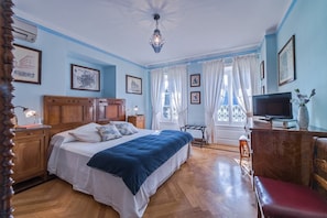 Ein Schlafzimmer mit einem hölzernen Bett, einem Fernseher und einem Schreibtisch mit Stuhl.