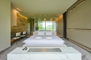 A modern hotel room with a large bed, a seating area with chairs, a glass shower enclosure, and a view of the outdoors. - Nero (Abuta)