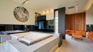 Un interior moderno con una bañera grande, una zona de estar y una obra de arte de gran tamaño.